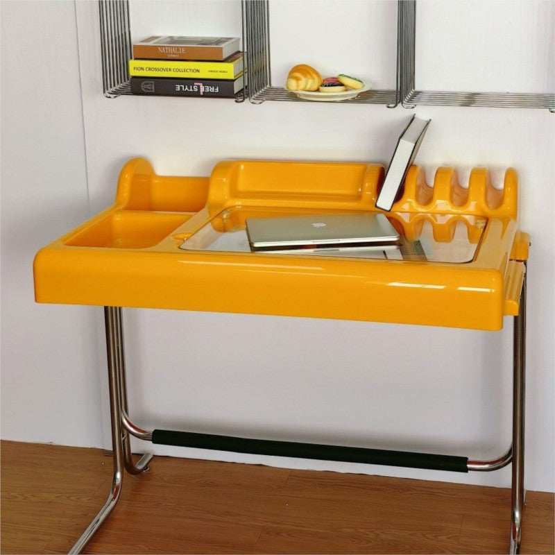 Orange-yellow vanity desk showing recessed organizer zones, glass work surface and chrome frame