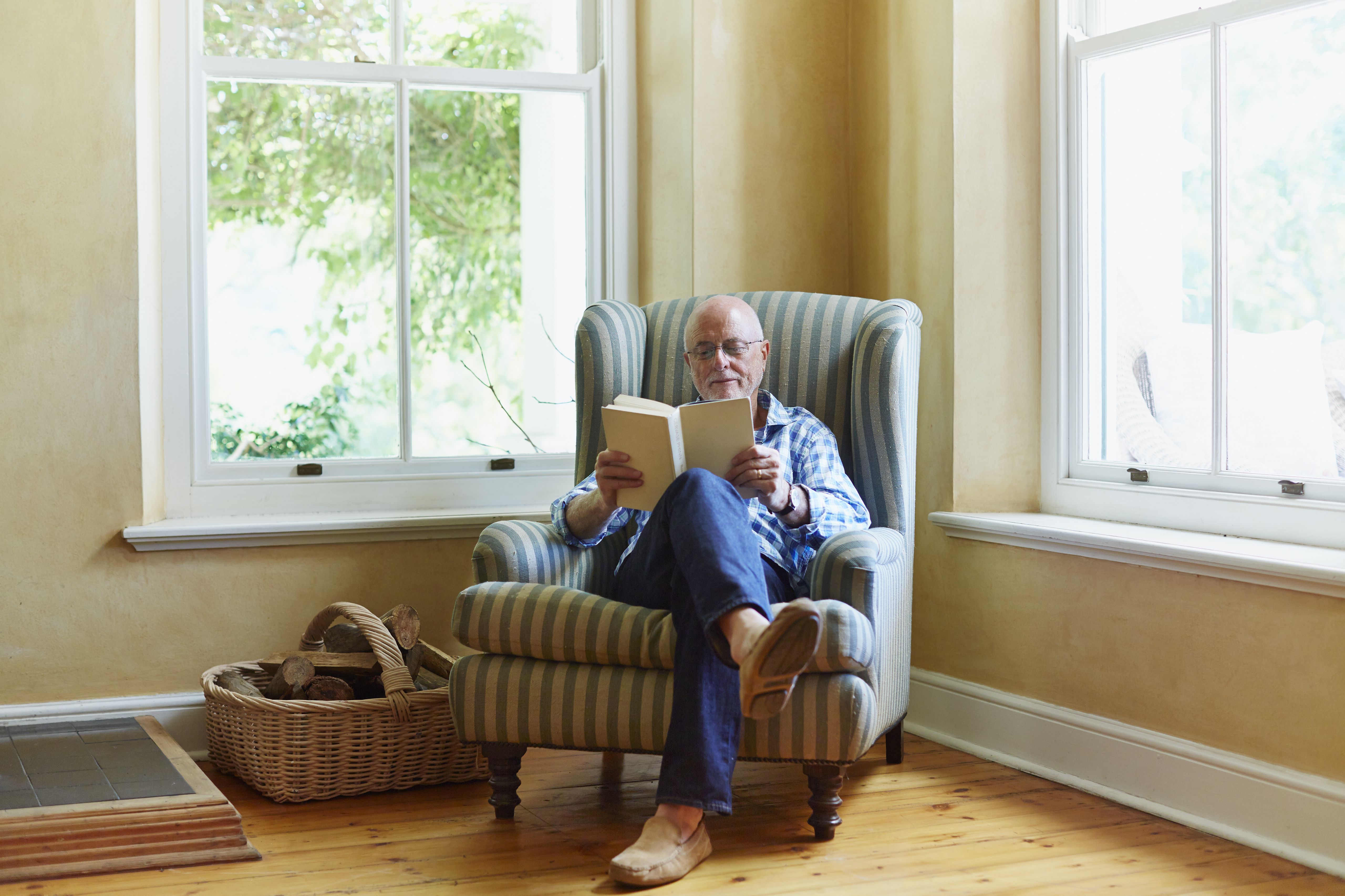 A person reading in an armchair by a window